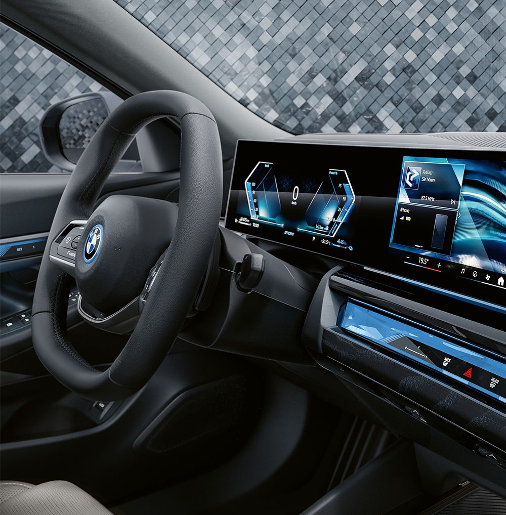 Nahaufnahme des Innenraums eines BMW mit elegantem Armaturenbrett, digitalen Anzeigen und einem Lederlenkrad