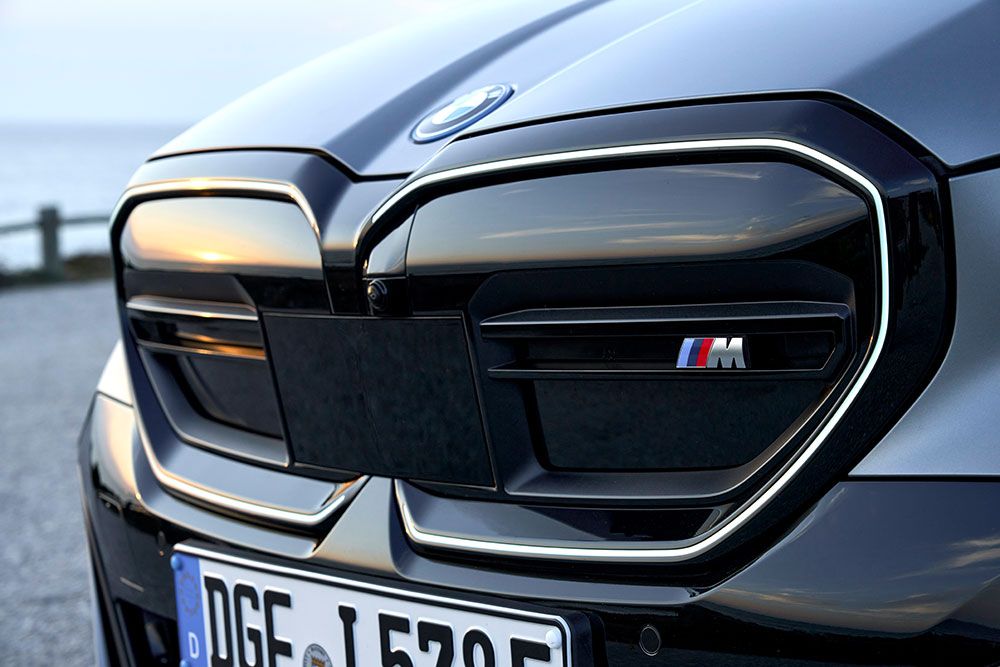 Nahaufnahme eines BMW M-Emblems auf einem eleganten Kühlergrill mit glänzend schwarzer Zierleiste